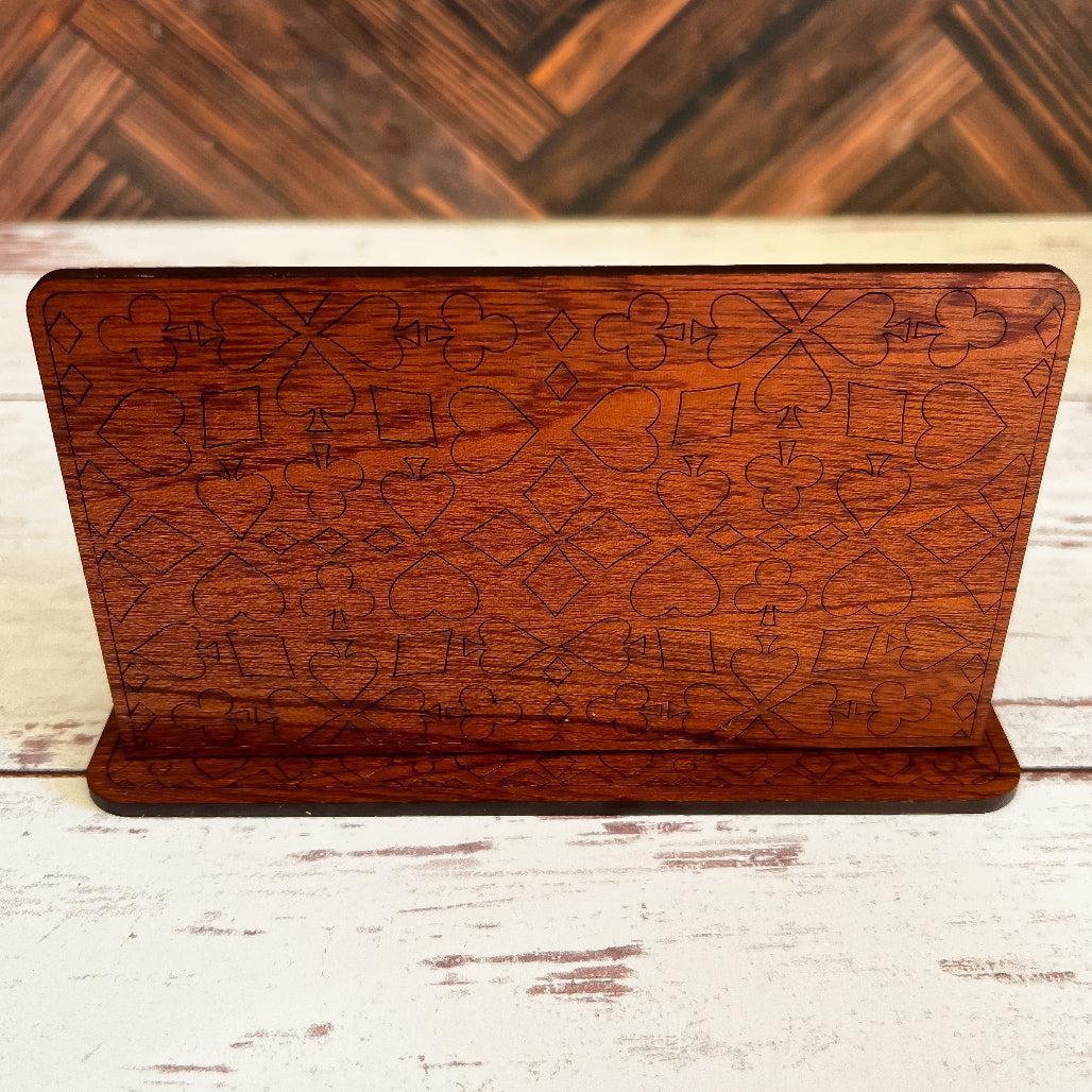 Wooden card holder with playing card symbol engraving on a wooden background