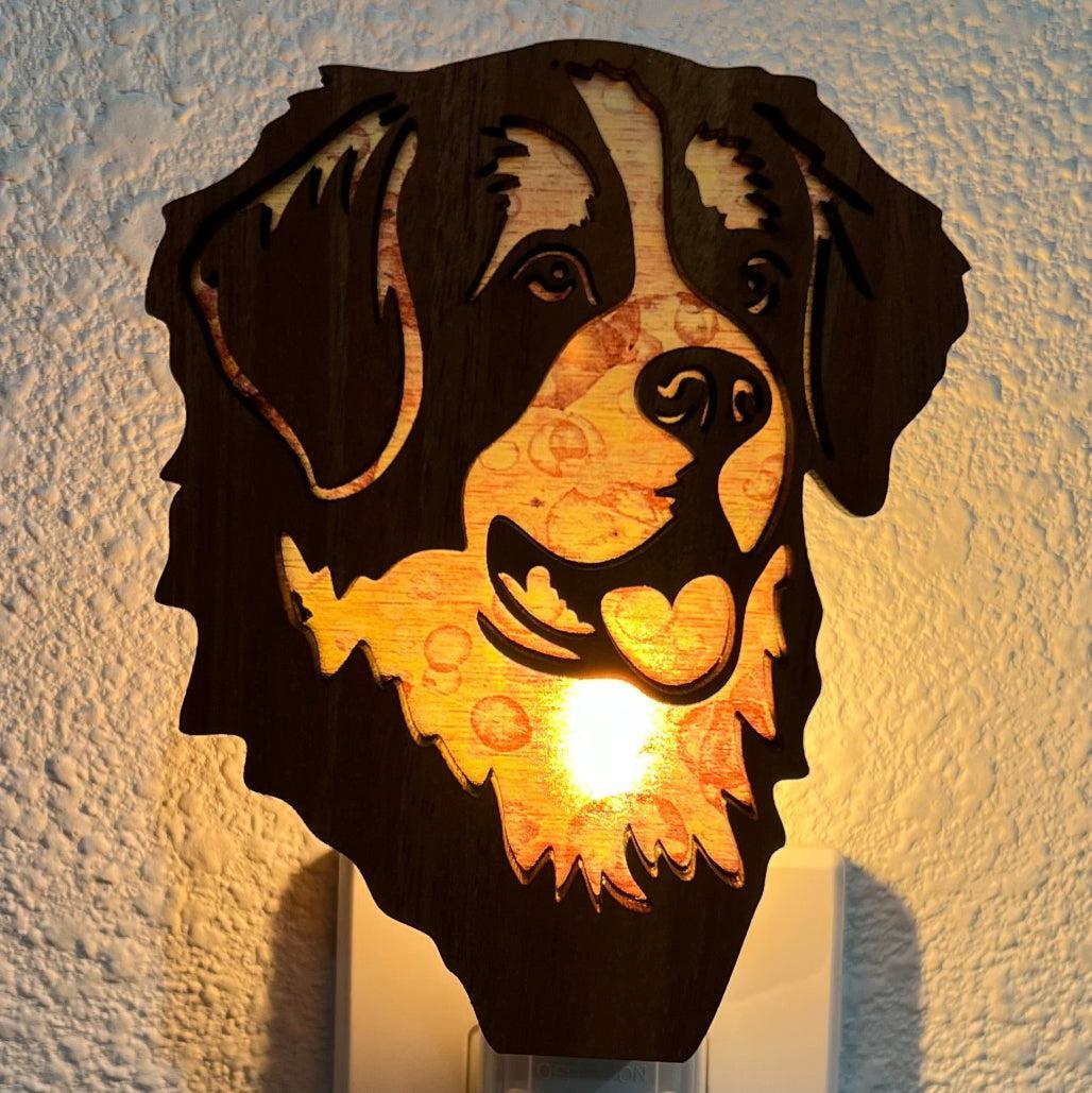 A laser-cut wooden night light in the shape of a dog's head, glowing with a warm light.