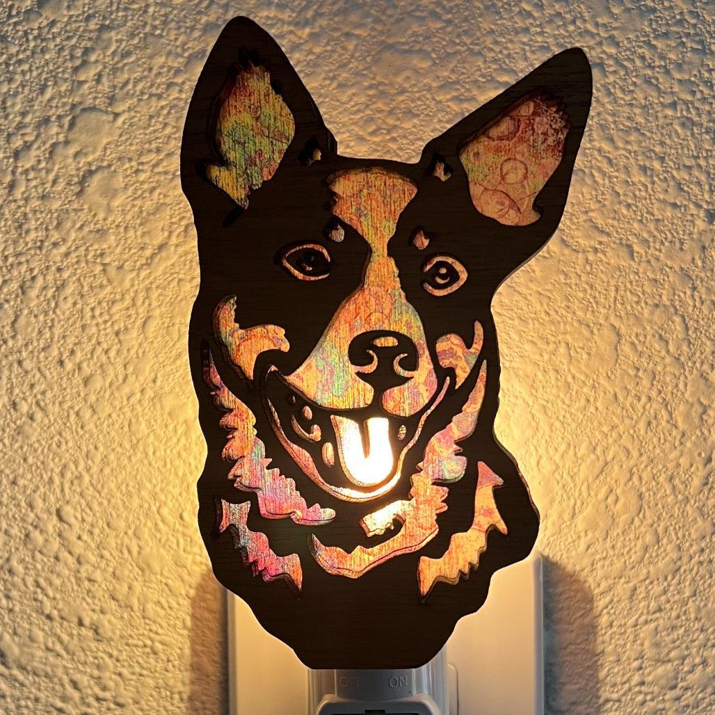 A laser-cut wooden night light in the shape of a dog's head, glowing with a warm light.