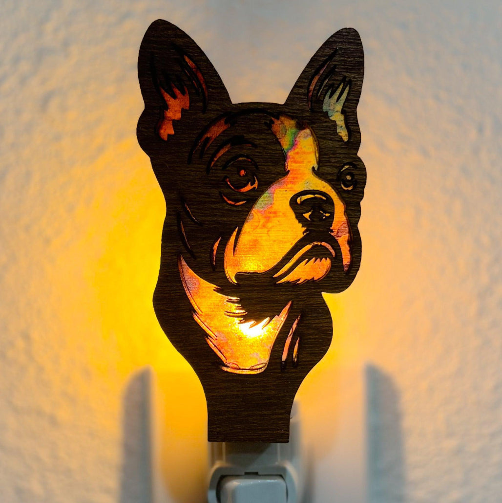 A laser-cut wooden night light in the shape of a dog's head, glowing with a warm light.