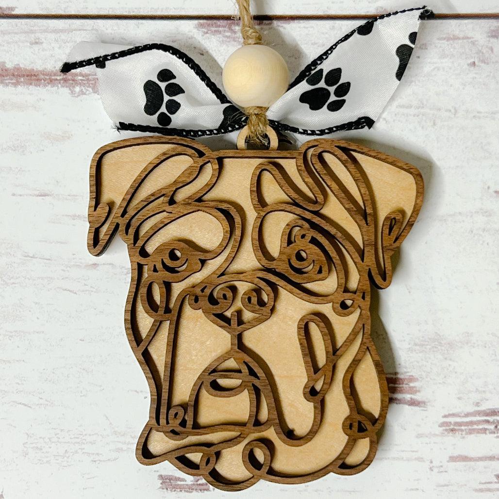 Laser-cut wooden doodle art dog ornament with paw print ribbon bow and bead, hanging on rustic twine.