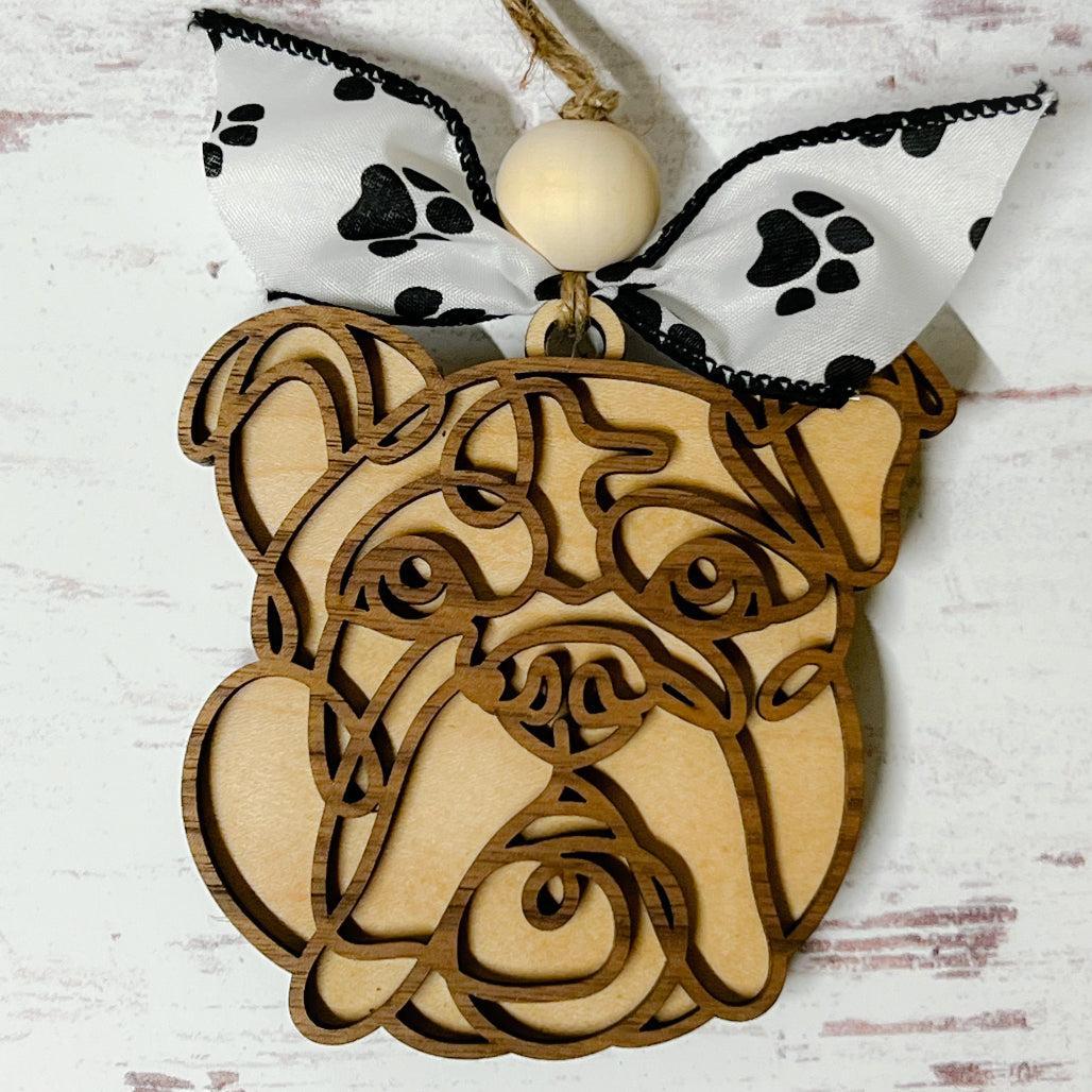 Laser-cut wooden doodle art dog ornament with paw print ribbon bow and bead, hanging on rustic twine.