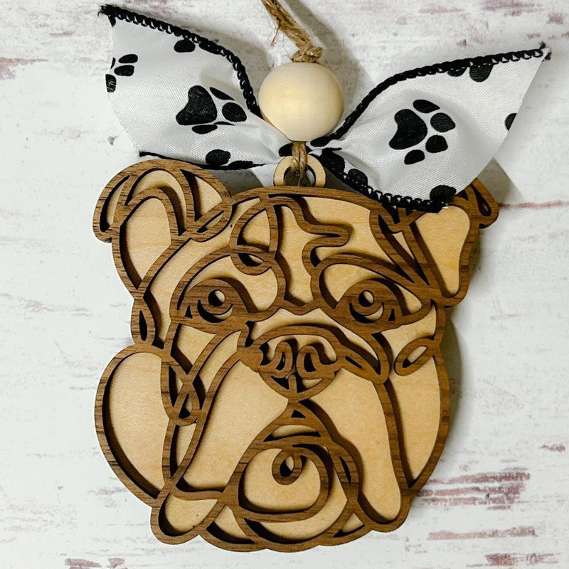 Laser-cut wooden doodle art dog ornament with paw print ribbon bow and bead, hanging on rustic twine.