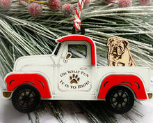 Load image into Gallery viewer, A vintage style red and white truck ornament with a dog riding in the back seat, placed on a branch with Christmas decorations.