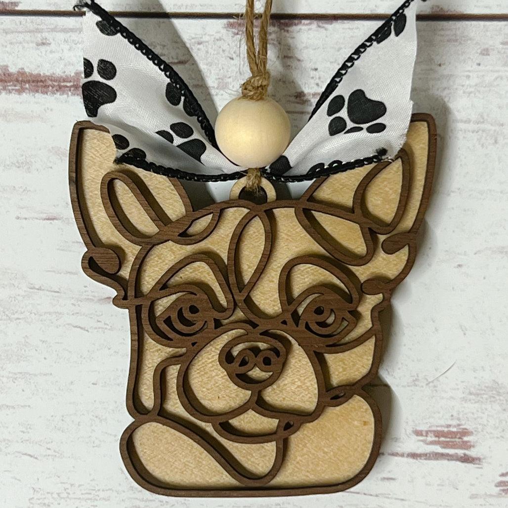 Laser-cut wooden doodle art dog ornament with paw print ribbon bow and bead, hanging on rustic twine.