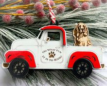 Load image into Gallery viewer, A vintage style red and white truck ornament with a dog riding in the back seat, placed on a branch with Christmas decorations.