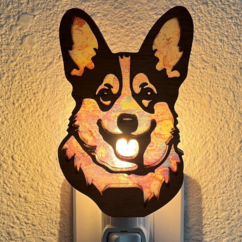 A laser-cut wooden night light in the shape of a dog's head, glowing with a warm light.