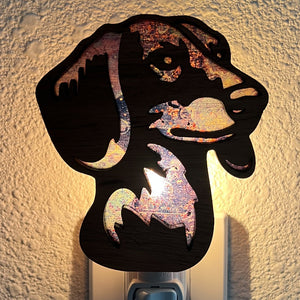 A laser-cut wooden night light in the shape of a dog's head, glowing with a warm light.