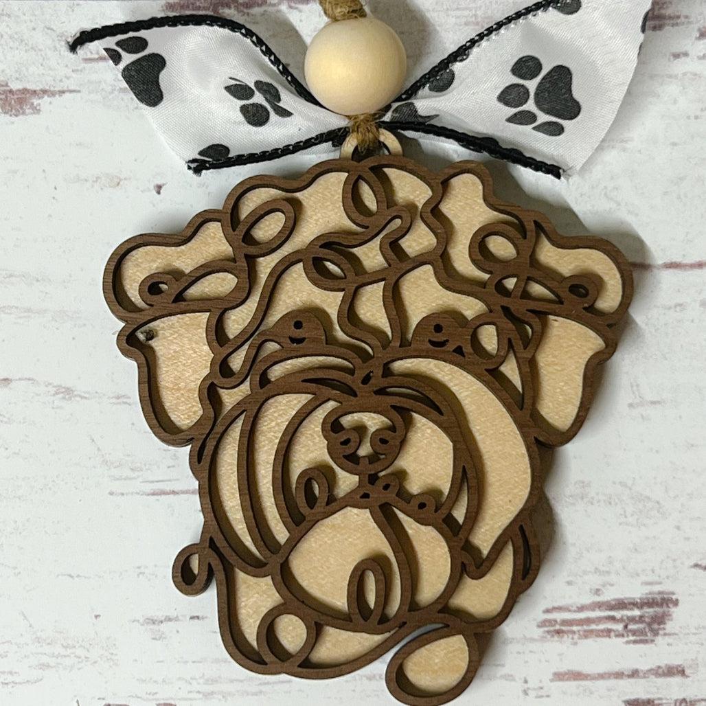 Laser-cut wooden doodle art dog ornament with paw print ribbon bow and bead, hanging on rustic twine.