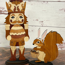 Load image into Gallery viewer, Wooden Easter décor set featuring a nutcracker with acorn crown and a squirrel with bunny ears holding a basket, displayed on a rustic wood surface.