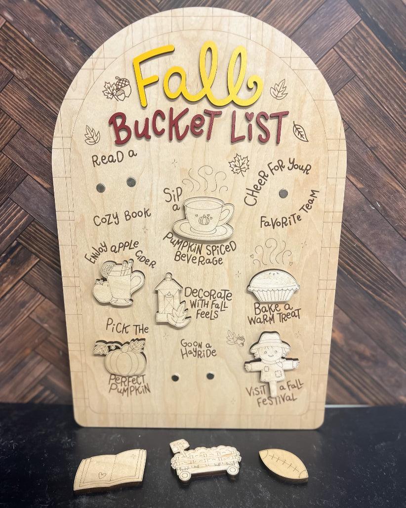 Wooden fall-themed bucket list board with cut-out pieces on a wooden surface