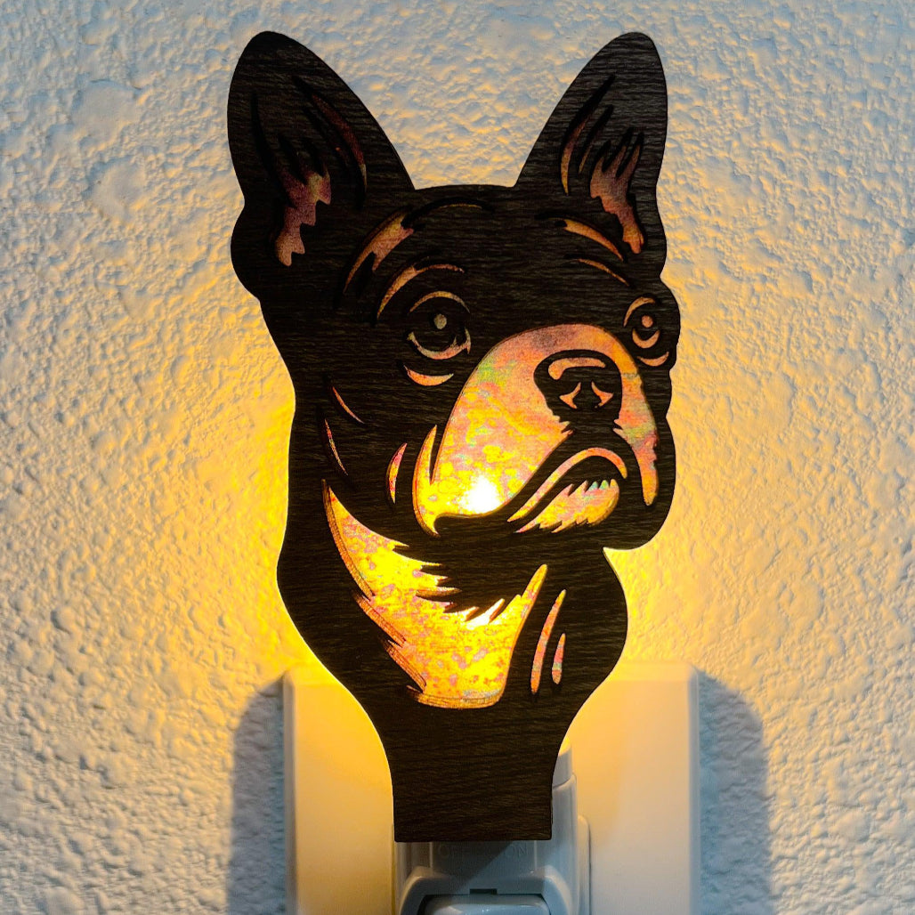 A laser-cut wooden night light in the shape of a dog's head, glowing with a warm light.