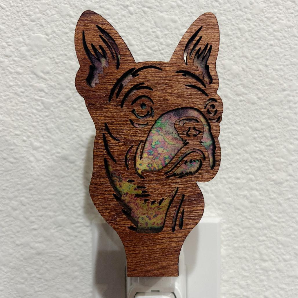 A laser-cut wooden night light in the shape of a dog's head, shown against a white wall.