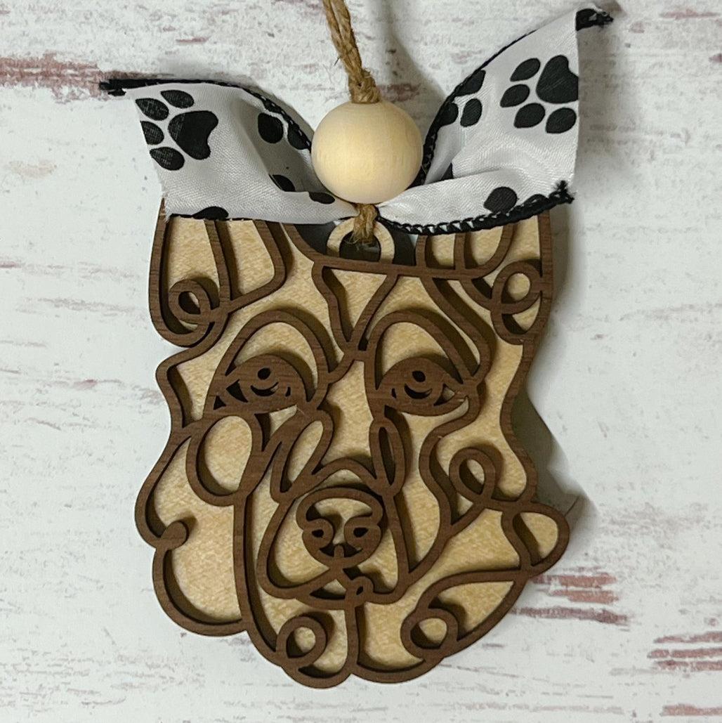 Laser-cut wooden doodle art dog ornament with paw print ribbon bow and bead, hanging on rustic twine.