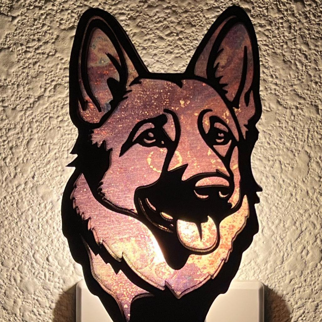 A laser-cut wooden night light in the shape of a dog's head, glowing with a warm light.