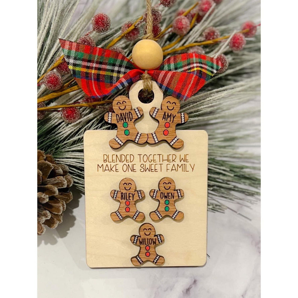 A wooden ornament featuring eight gingerbread man shapes with the ability to personalize with names, adorned with a red and green ribbon and a small bead.
