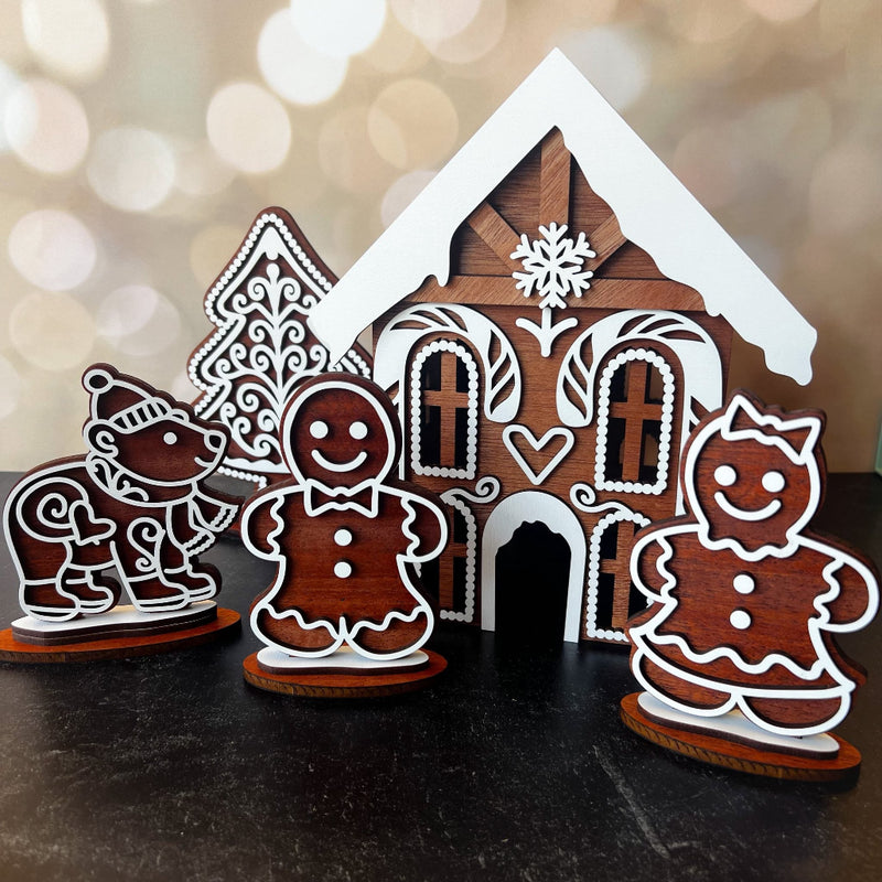 Wooden gingerbread house and figures on a dark surface with a blurred light background