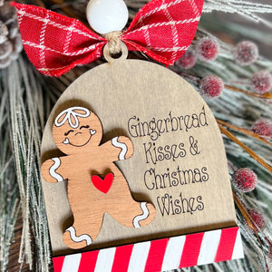 A wooden gingerbread man ornament with a red and white striped bow, featuring the text 'Gingerbread Kisses & Christmas Wishes'.