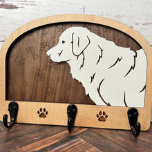 Load image into Gallery viewer, A wooden dog leash holder with a cut-out silhouette of a dog and the phrase &#39;Unleash Adventure&#39;. It features three hooks at the bottom and paw prints around the dog&#39;s silhouette.