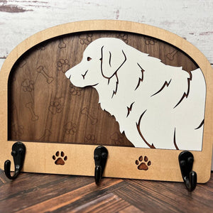 A wooden dog leash holder with a cut-out silhouette of a dog and the phrase 'Unleash Adventure'. It features three hooks at the bottom and paw prints around the dog's silhouette.
