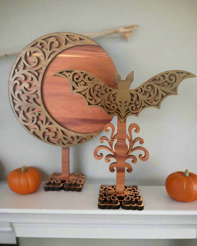 Wooden decorative item with bat and crescent moon design on a blurred background