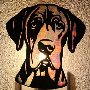 A laser-cut wooden night light in the shape of a dog's head, glowing with a warm light.
