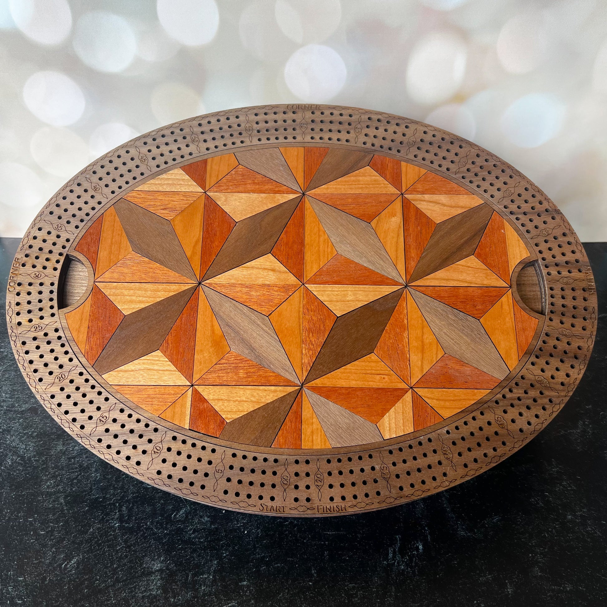 Wooden cribbage board with geometric pattern on a dark surface