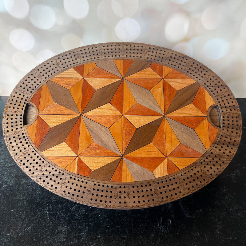 Wooden cribbage board with geometric pattern on a dark surface