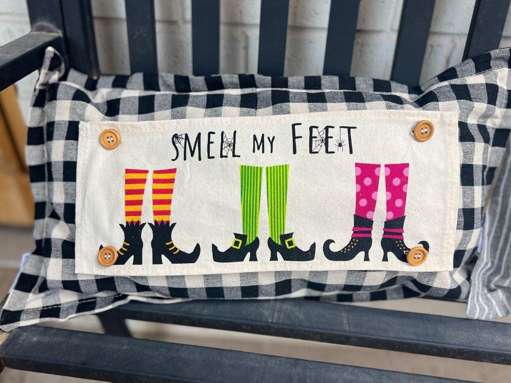 Decorative pillow with witch feet design and 'Smell my Feet' text on a striped background.