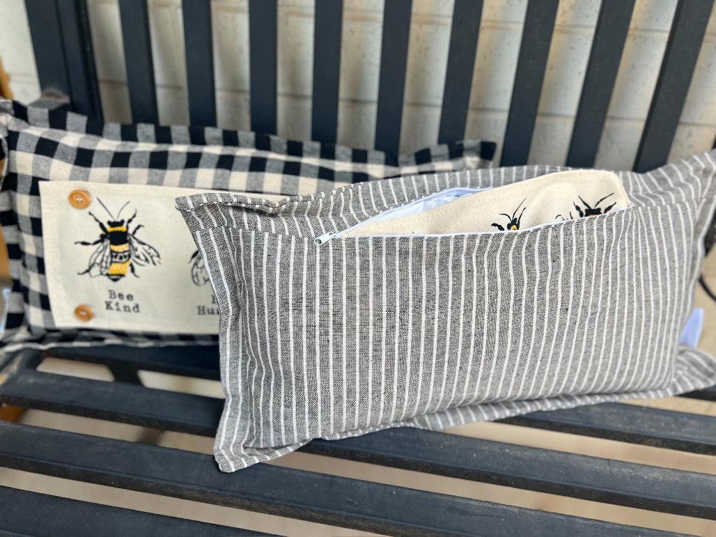 Striped pillow with bee design on a wooden surface