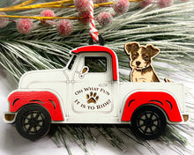 Load image into Gallery viewer, A vintage style red and white truck ornament with a dog riding in the back seat, placed on a branch with Christmas decorations.