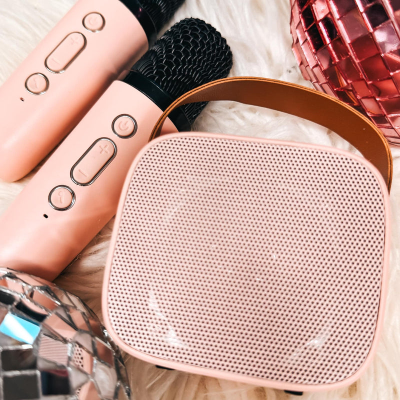 Two mini wireless karaoke speakers in pink and white colors with a Bluetooth remote control and two microphones.