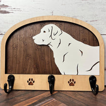 Load image into Gallery viewer, A wooden dog leash holder with a cut-out silhouette of a dog and the phrase &#39;Unleash Adventure&#39;. It features three hooks at the bottom and paw prints around the dog&#39;s silhouette.
