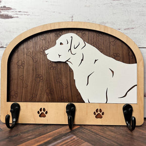 A wooden dog leash holder with a cut-out silhouette of a dog and the phrase 'Unleash Adventure'. It features three hooks at the bottom and paw prints around the dog's silhouette.