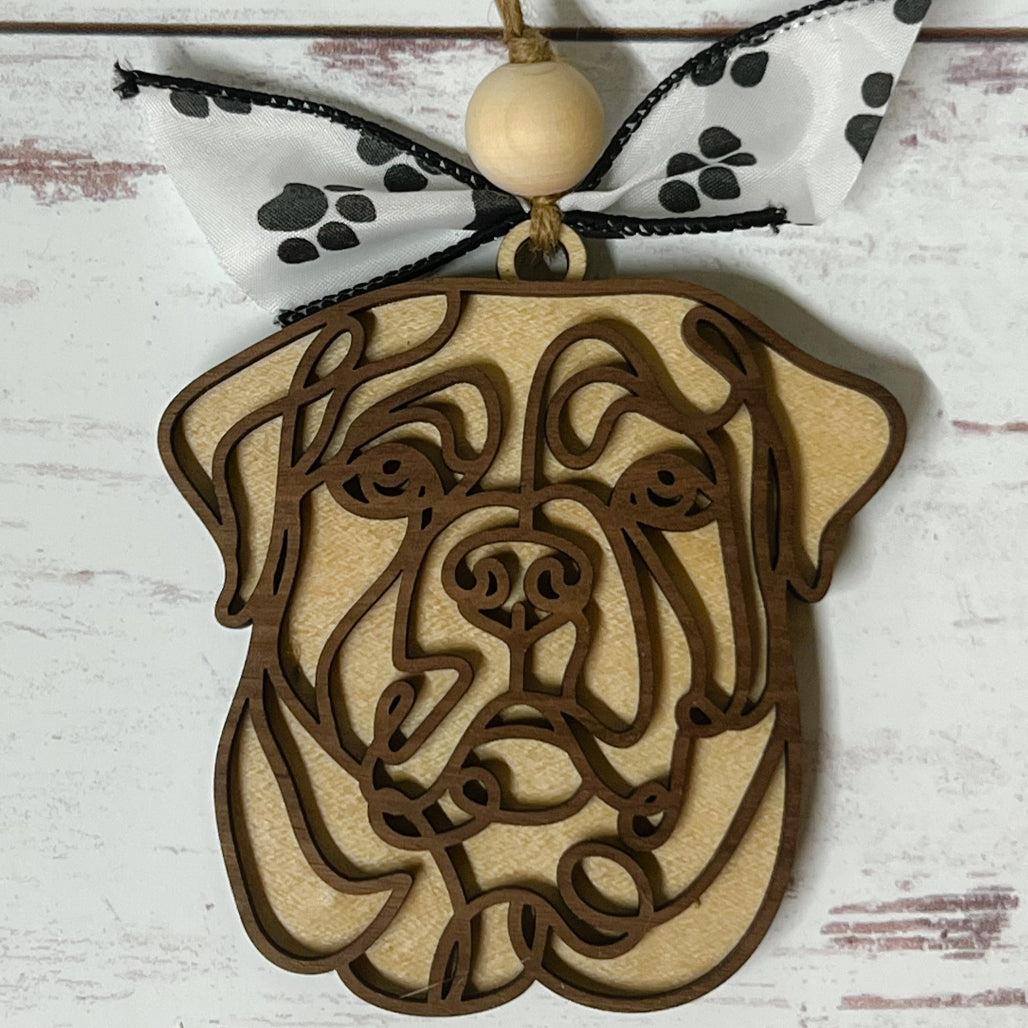 Laser-cut wooden doodle art dog ornament with paw print ribbon bow and bead, hanging on rustic twine.