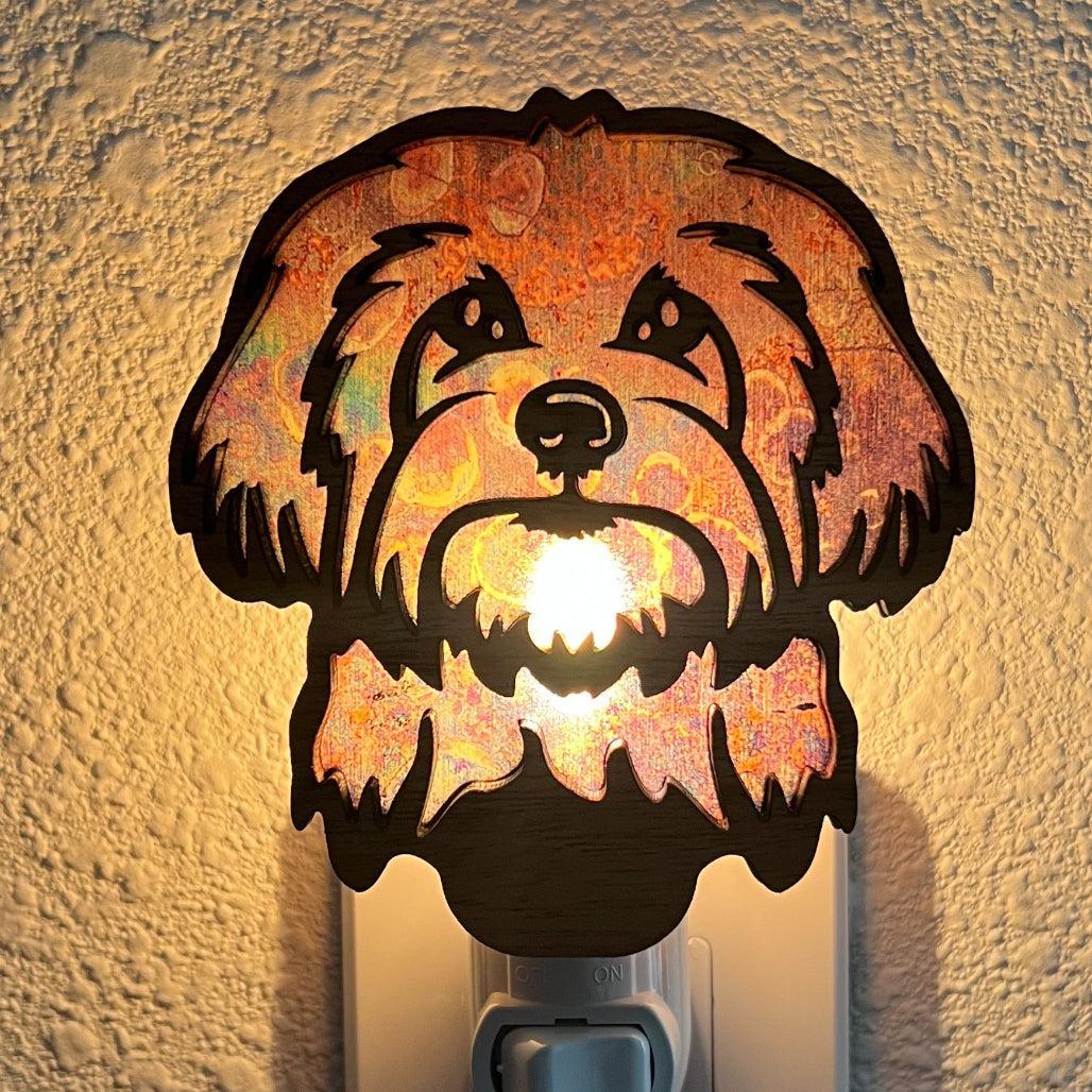 A laser-cut wooden night light in the shape of a dog's head, glowing with a warm light.