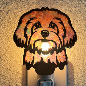 A laser-cut wooden night light in the shape of a dog's head, glowing with a warm light.