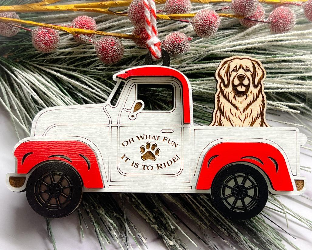 A vintage style red and white truck ornament with a dog riding in the back seat, placed on a branch with Christmas decorations.