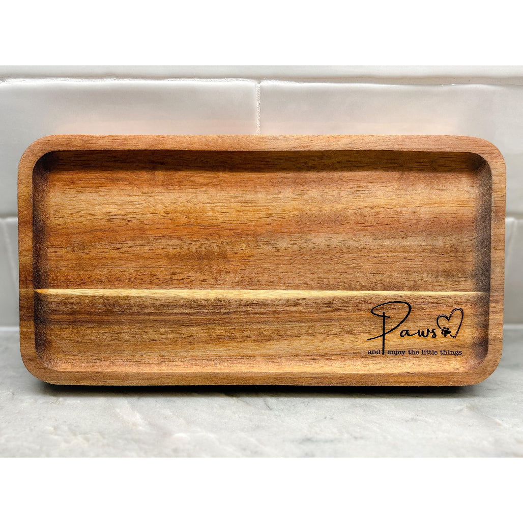 Wooden valet tray engraved with “Paws ♥ and enjoy the little things” on marble counter with tile background.