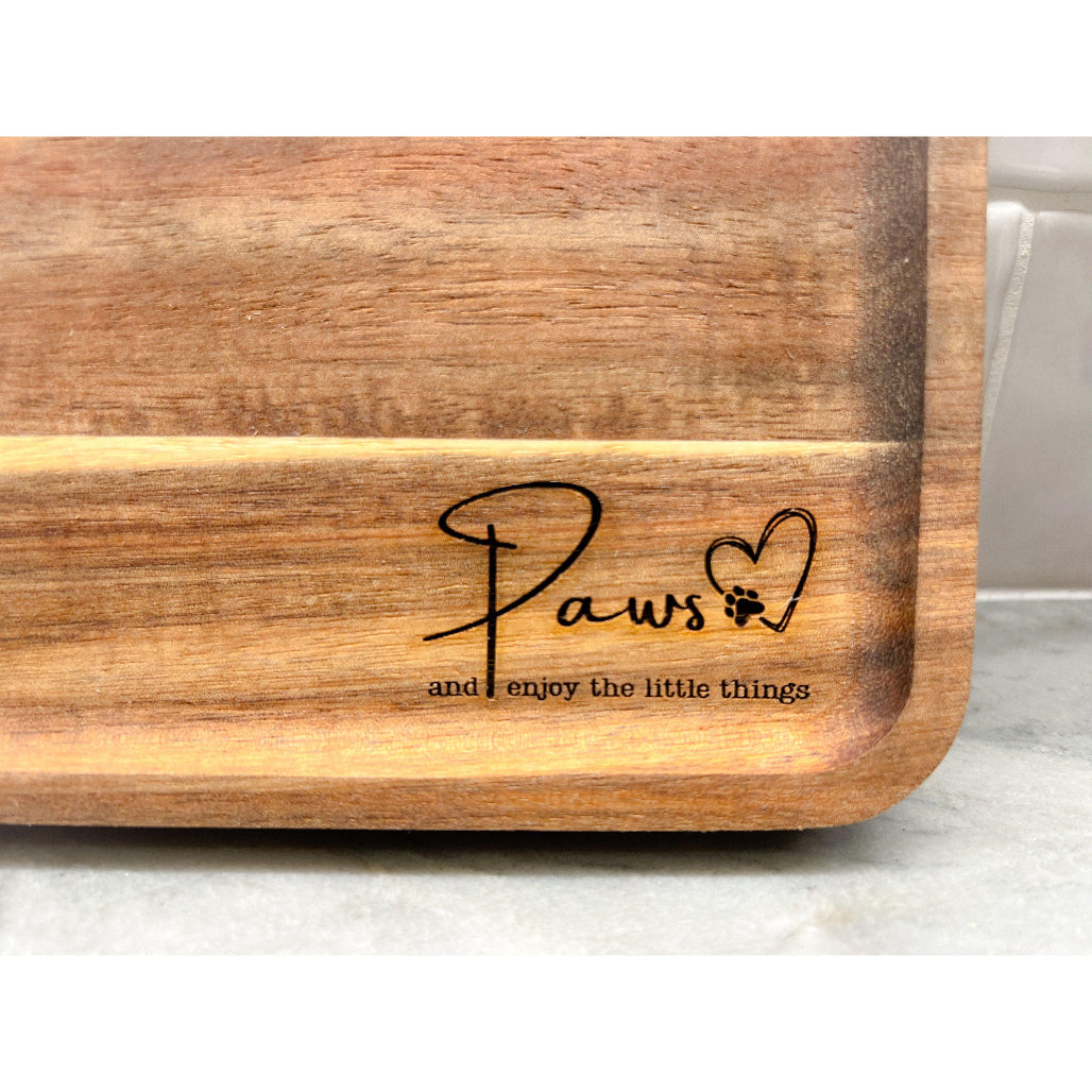 Wooden valet tray engraved with “Paws ♥ and enjoy the little things” on marble counter with tile background.