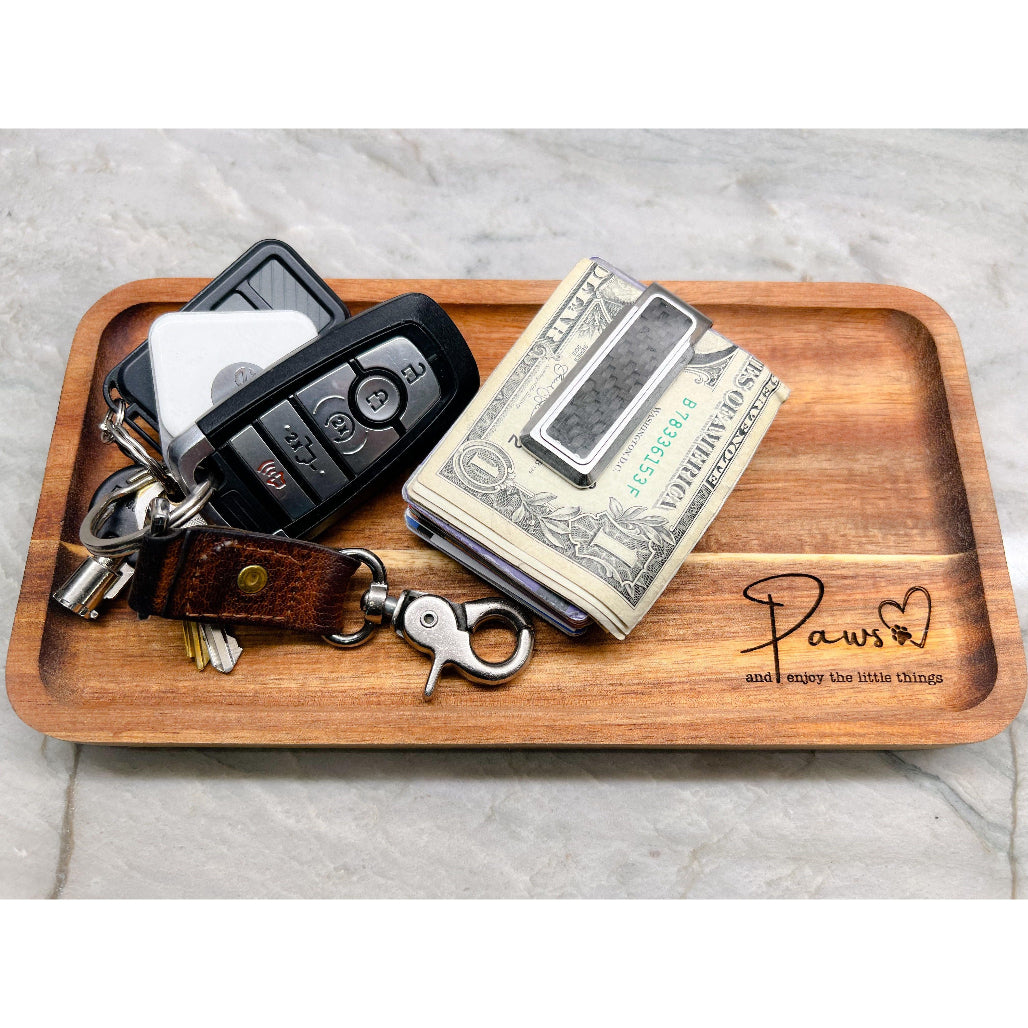 Wooden valet tray engraved with “Paws ♥ and enjoy the little things” on marble counter with tile background.