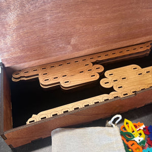 Wooden toy components on a wooden shelf with colorful items below.