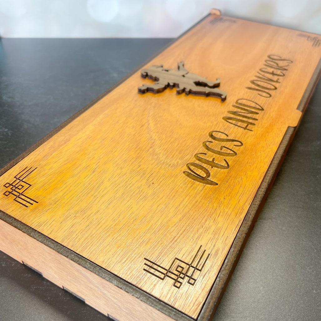 Wooden box with engraved text and design on a gray surface