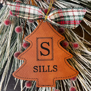 Brown leatherette tree ornament with greenery and berry background