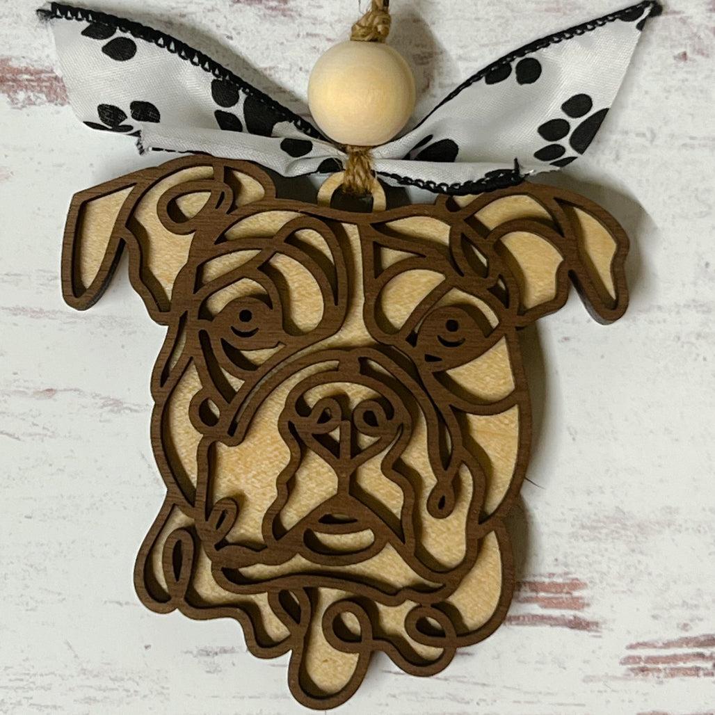 Laser-cut wooden doodle art dog ornament with paw print ribbon bow and bead, hanging on rustic twine.