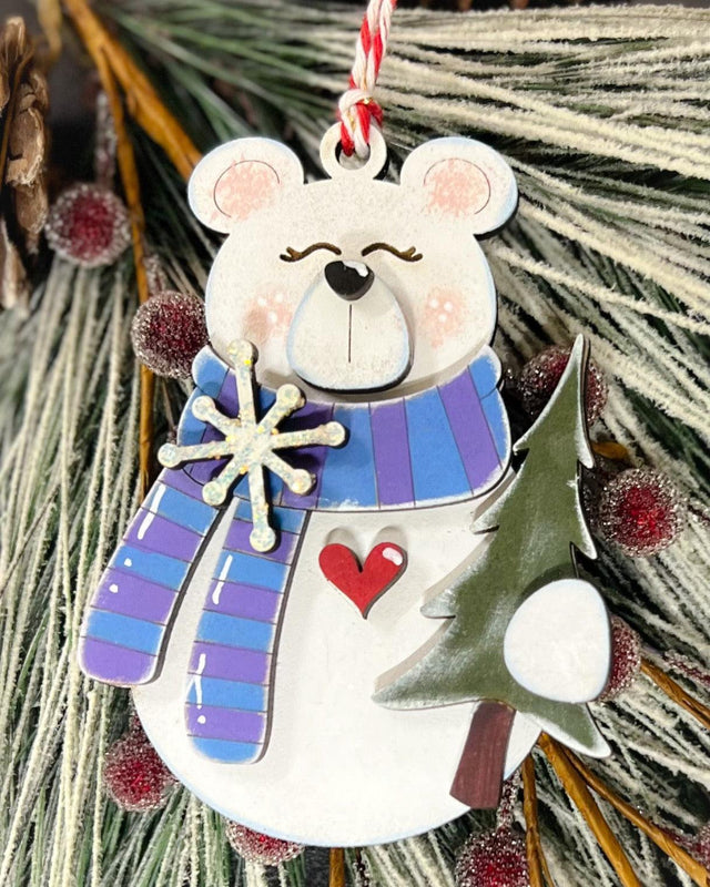 Decorative white bear ornament with a striped scarf holding a tree.