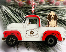 Load image into Gallery viewer, A vintage style red and white truck ornament with a dog riding in the back seat, placed on a branch with Christmas decorations.