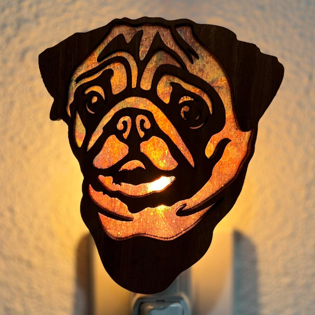 A laser-cut wooden night light in the shape of a dog's head, glowing with a warm light.