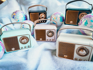Collection of vintage-style radios on a white blanket with disco balls around them