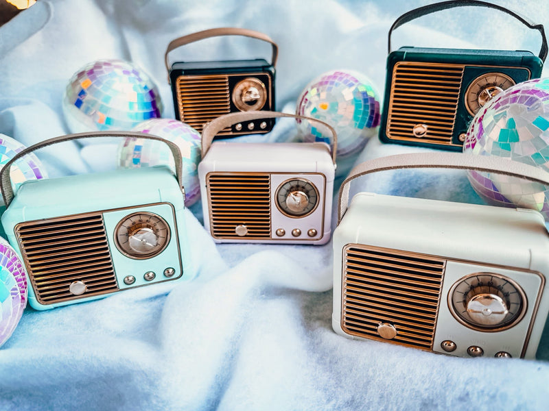 Collection of vintage-style radios on a white blanket with disco balls around them